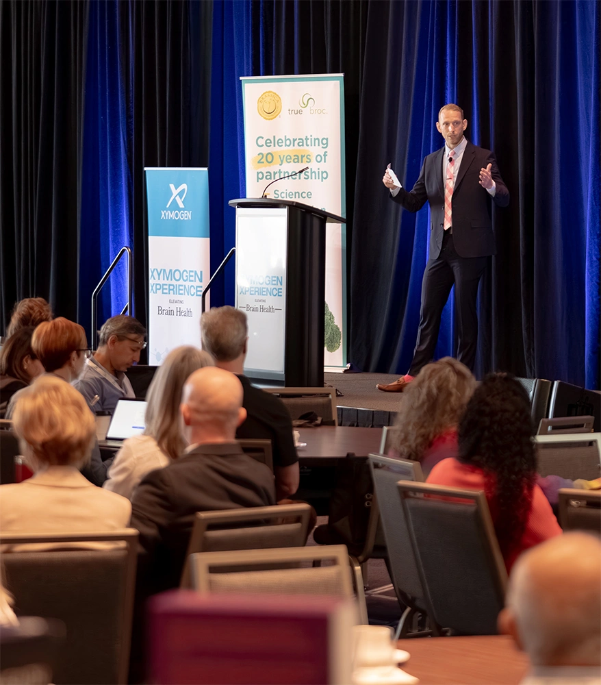 Dr. James Munro speaking onstage as attendees watch
